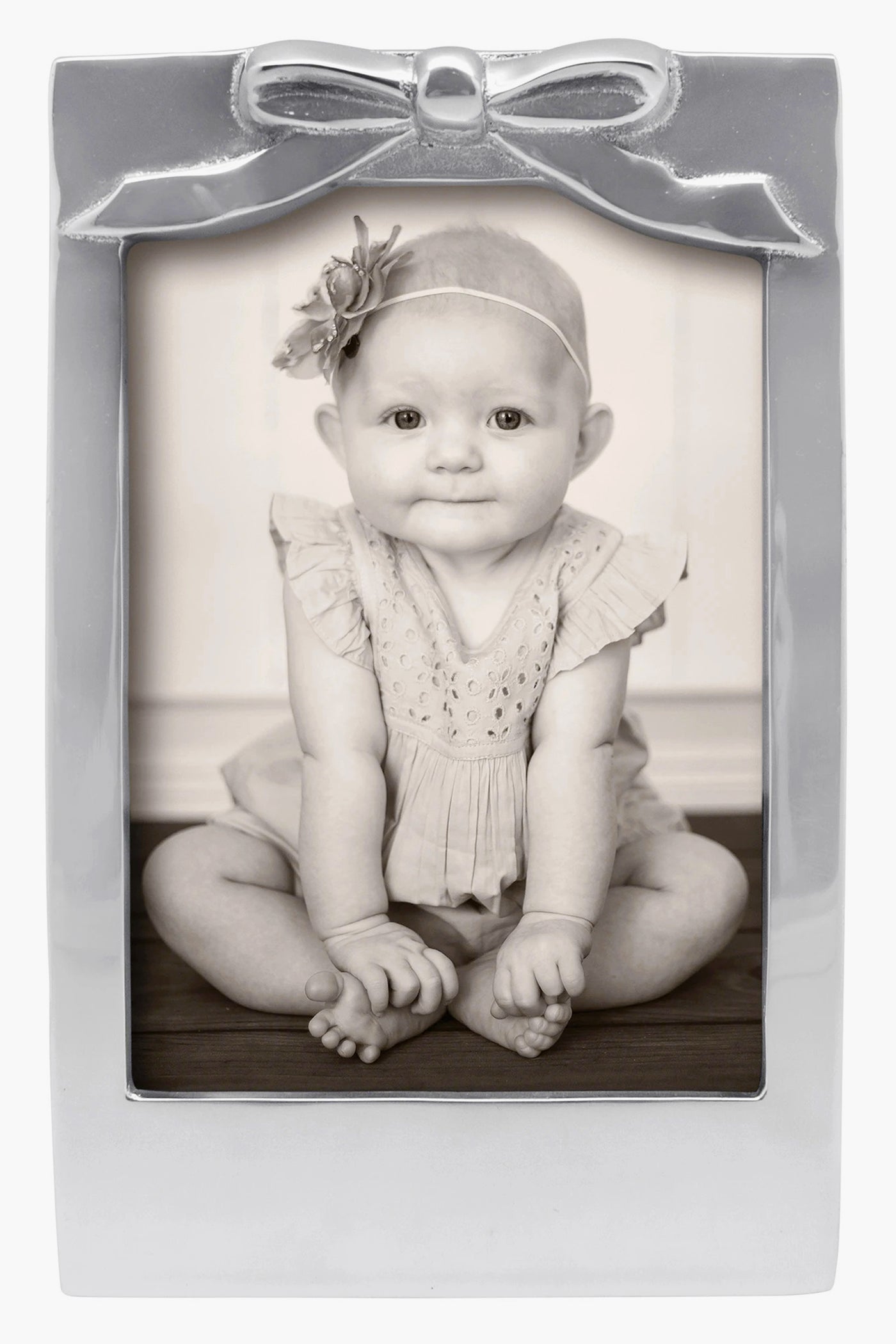 Black-and-white photo of a baby in a Mariposa 5x7 recycled aluminum frame with bow detail and flower headband—ideal as a baby shower gift.
