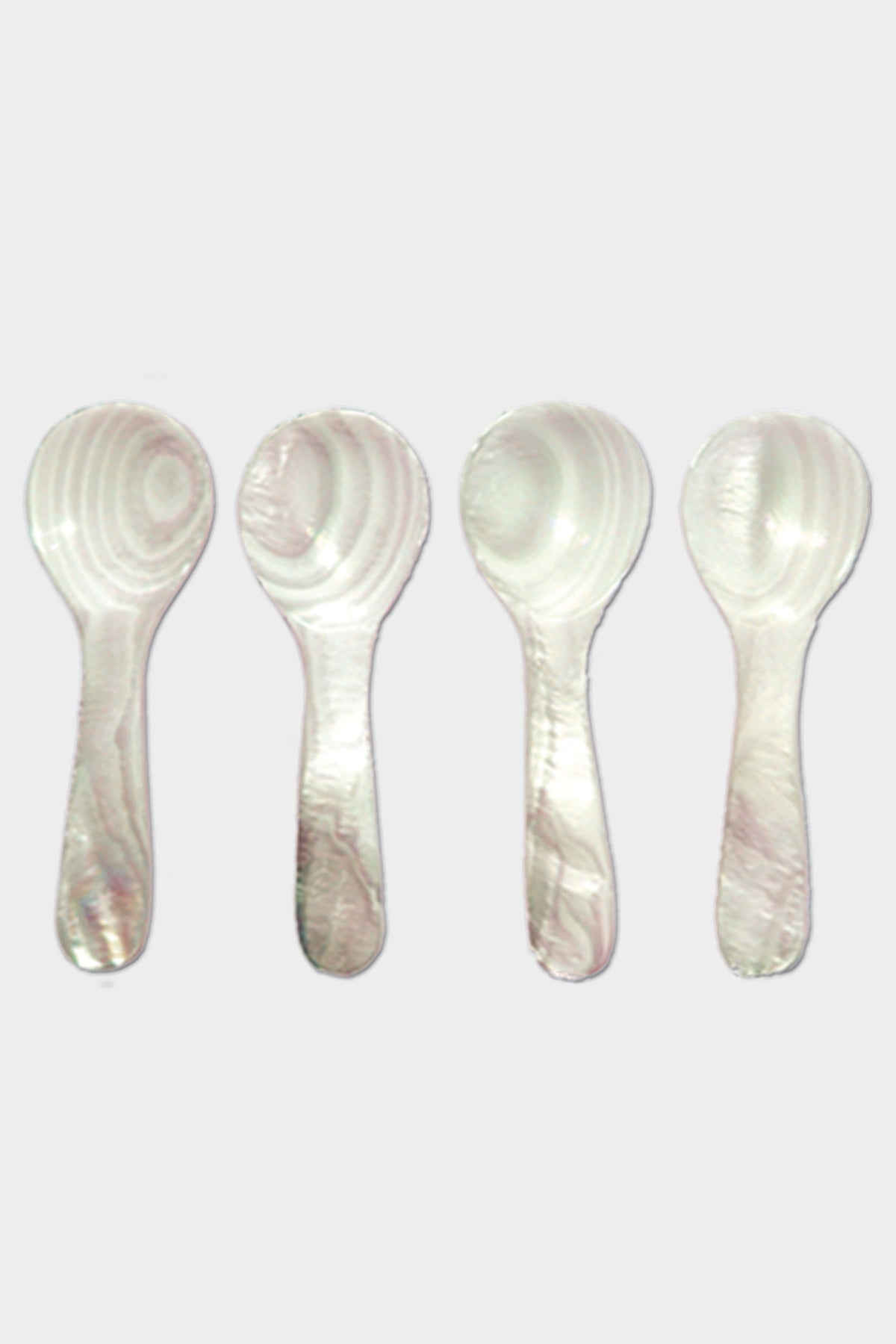Four white plastic spoons by Be Home, featuring a marbled pattern inspired by Mother of Pearl, are arranged vertically in a row.