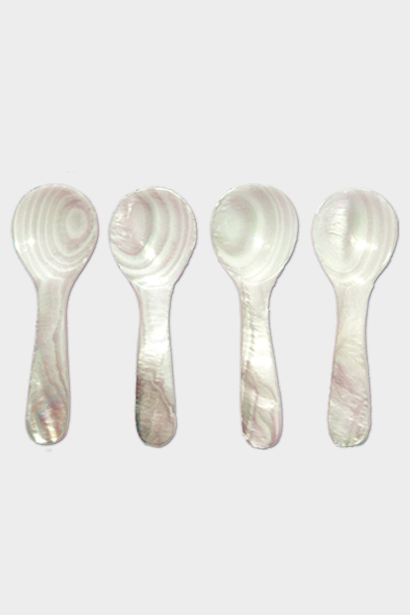 Four white plastic spoons by Be Home, featuring a marbled pattern inspired by Mother of Pearl, are arranged vertically in a row.