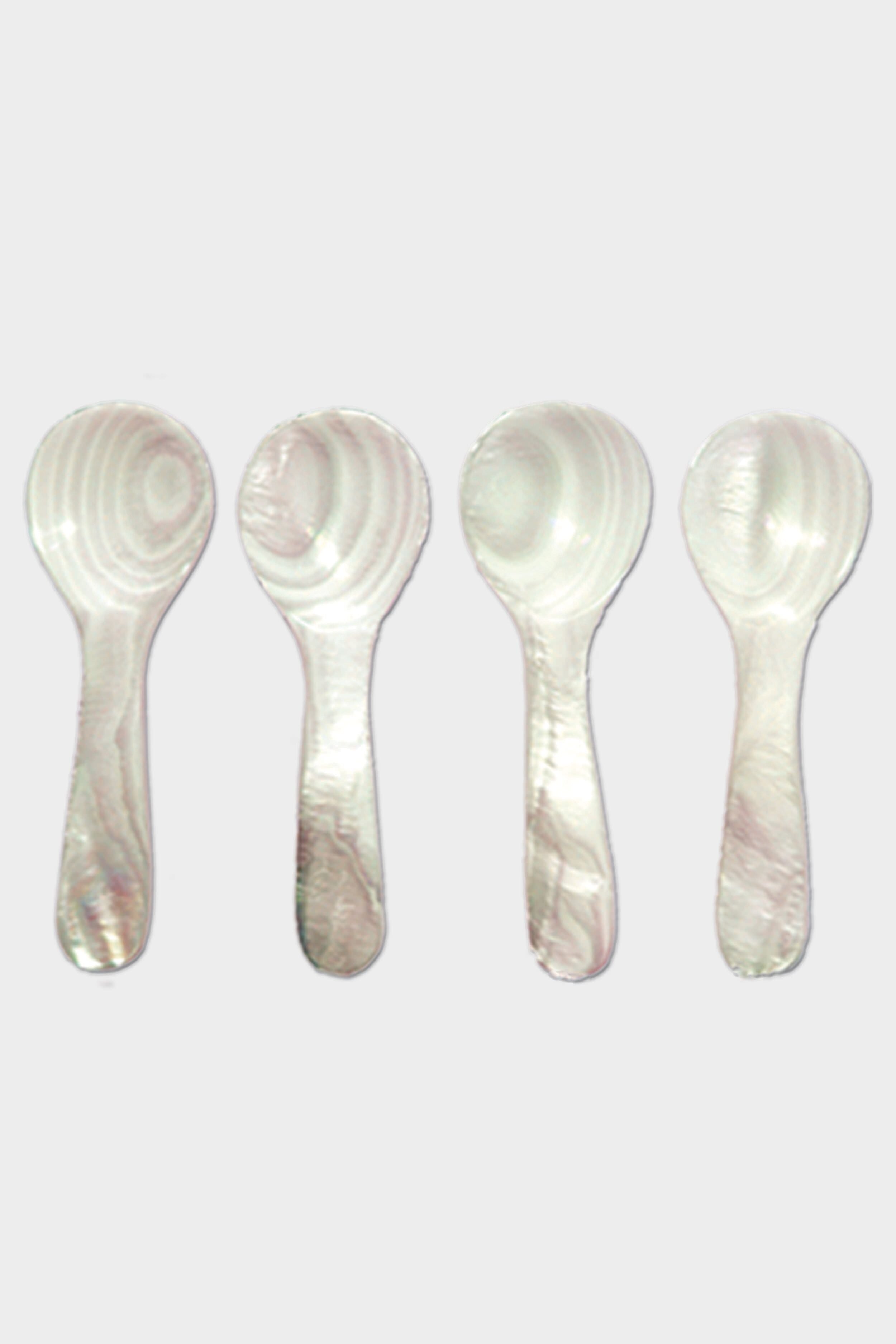 Four white plastic spoons by Be Home, featuring a marbled pattern inspired by Mother of Pearl, are arranged vertically in a row.