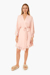 An Eberjey model faces forward in a light pink kimono robe with lace trim and waist tie—part of our super-soft pajama sets—paired with beige fuzzy slippers.
