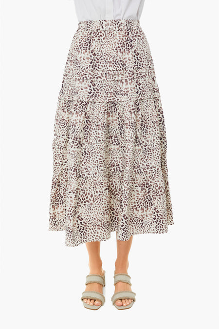 A person wears a white shirt, a Sea New York midi skirt featuring an animal print and smocked waist, and beige sandals.