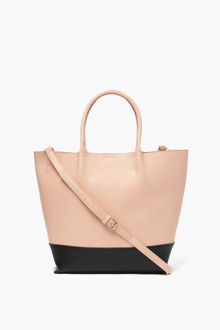 The Urban Originals tote is a two-tone vegan leather bag with a beige upper, black base, two handles, and an adjustable shoulder strap—offering cruelty-free style in an eco-conscious design.