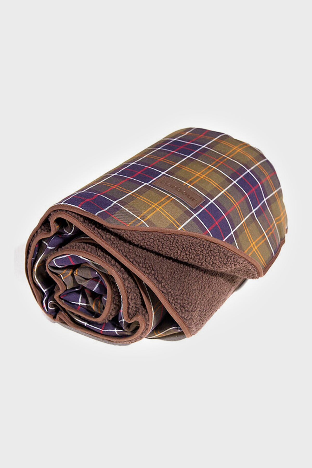 The Barbour rolled-up tartan dog blanket features a brown fleece side and a plaid patterned fabric on the reverse, offering cozy comfort for your pet.