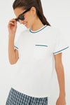 A woman in Tnuck Sport sunglasses, a White Piped Cotton Tee with blue and teal trim, and patterned blue shorts creates a fresh, sporty vibe.