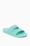 A single light teal Freedom Moses women’s slide sandal with two buckle straps, contoured footbed, and textured sole—crafted for sustainability and ideal as waterproof sandals.