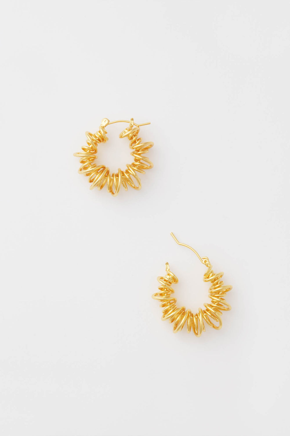 A pair of Petit Moments Gold Riele Earrings featuring a textured, spiked design and classic spiral hoops for an eye-catching look.