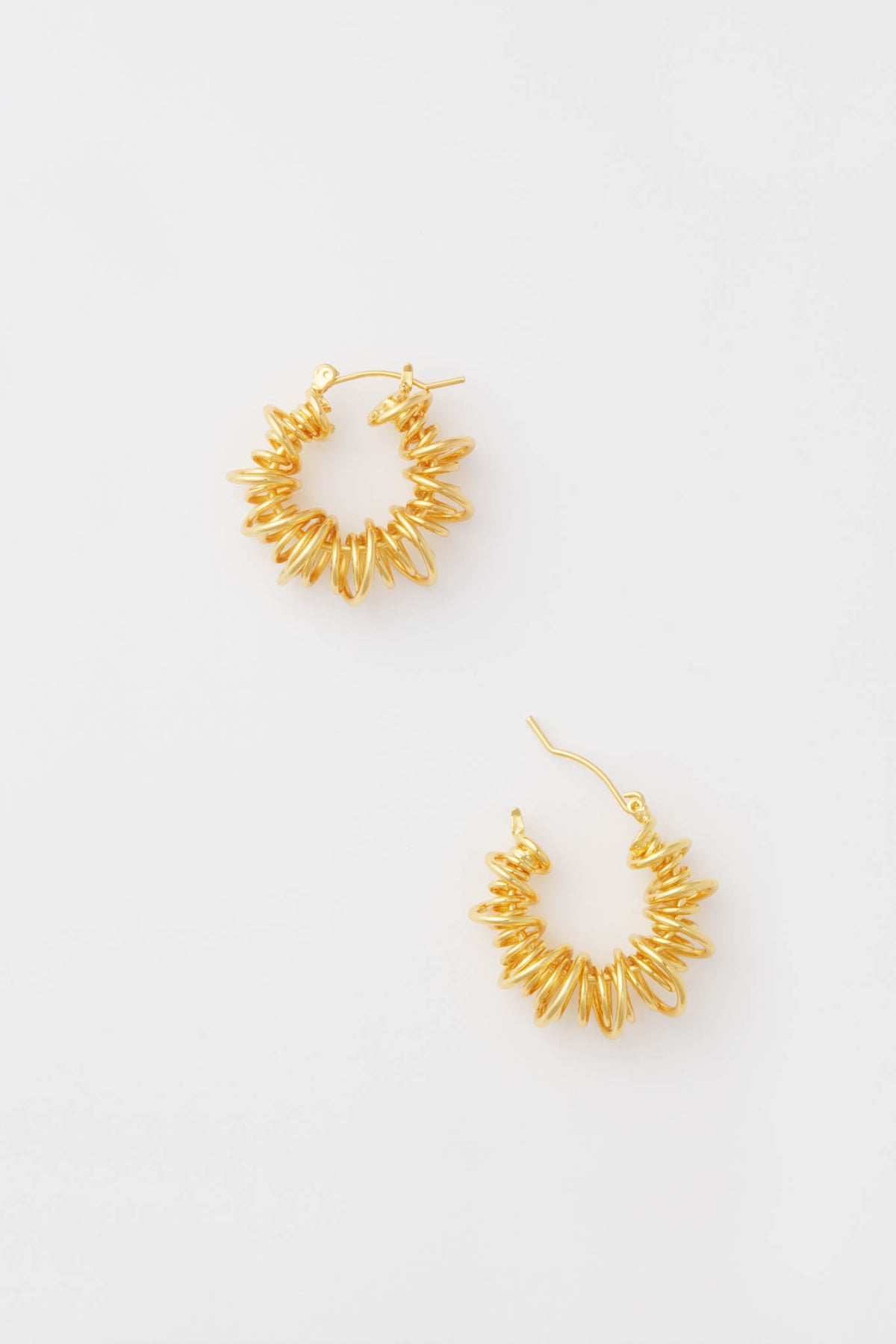 A pair of Petit Moments Gold Riele Earrings featuring a textured, spiked design and classic spiral hoops for an eye-catching look.