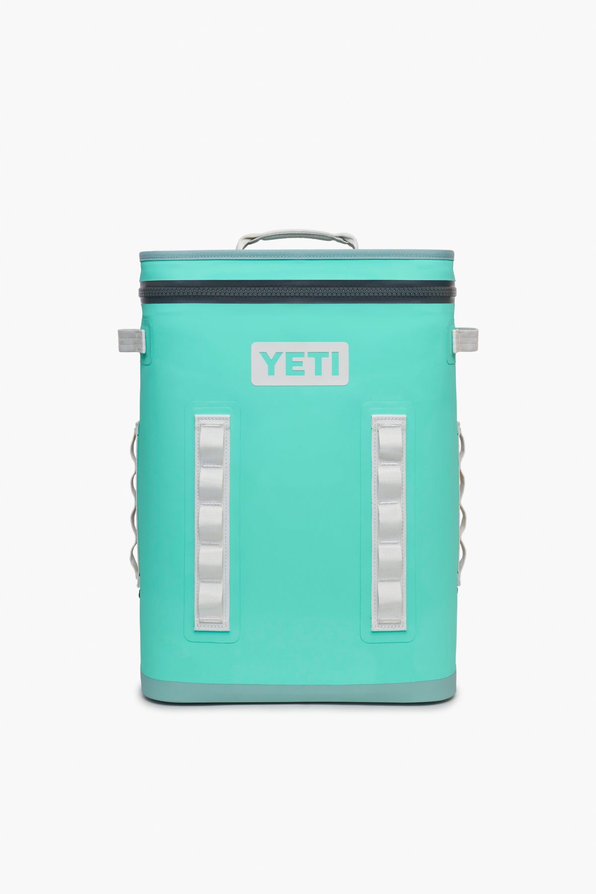 A YETI Hopper BackFlip 24 backpack cooler in teal with a zippered top, sturdy handle, and white accents is shown. This leakproof cooler is ideal for carrying drinks wherever you go.