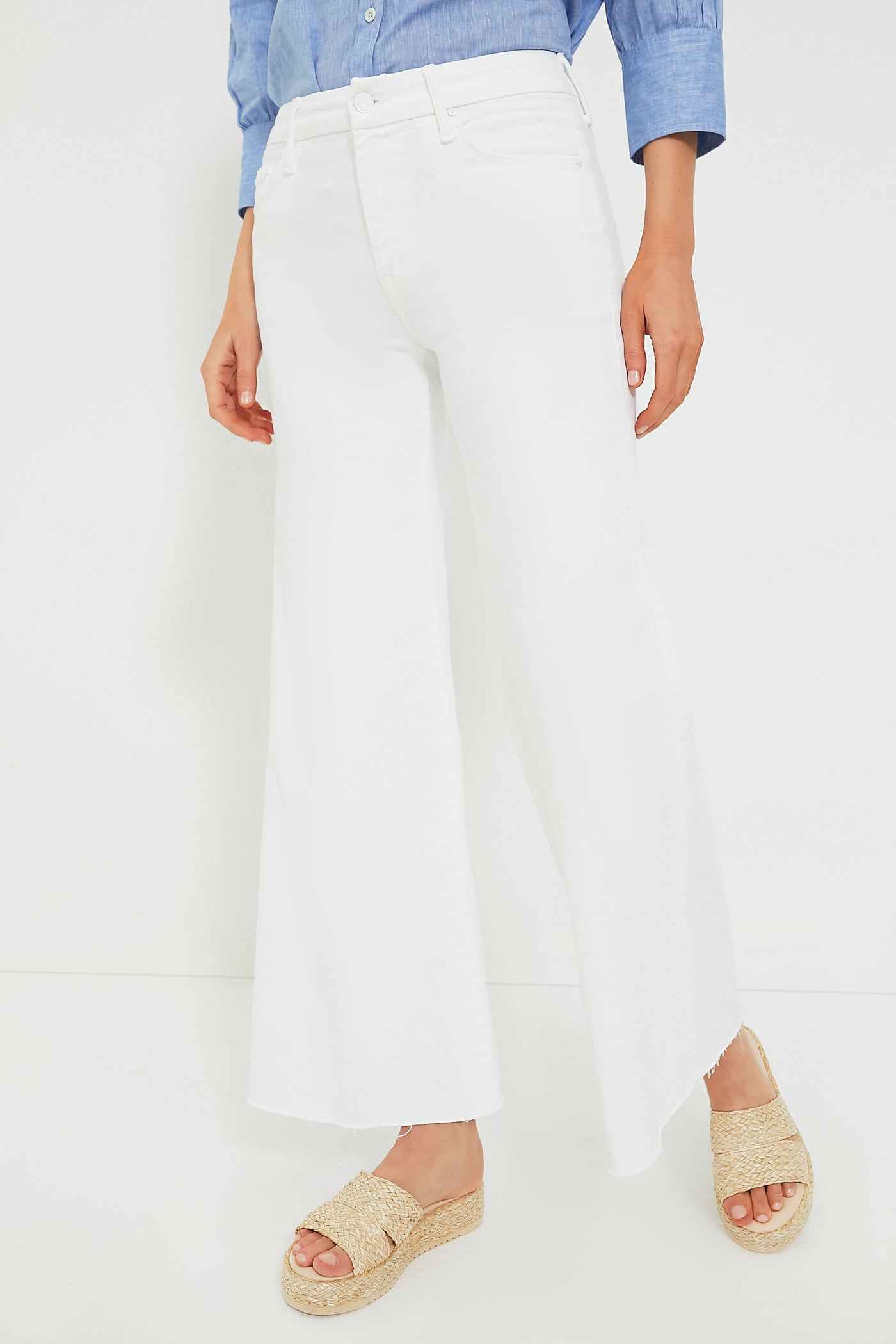 Person in a blue shirt, MOTHER white wide leg jeans, and beige platform sandals.