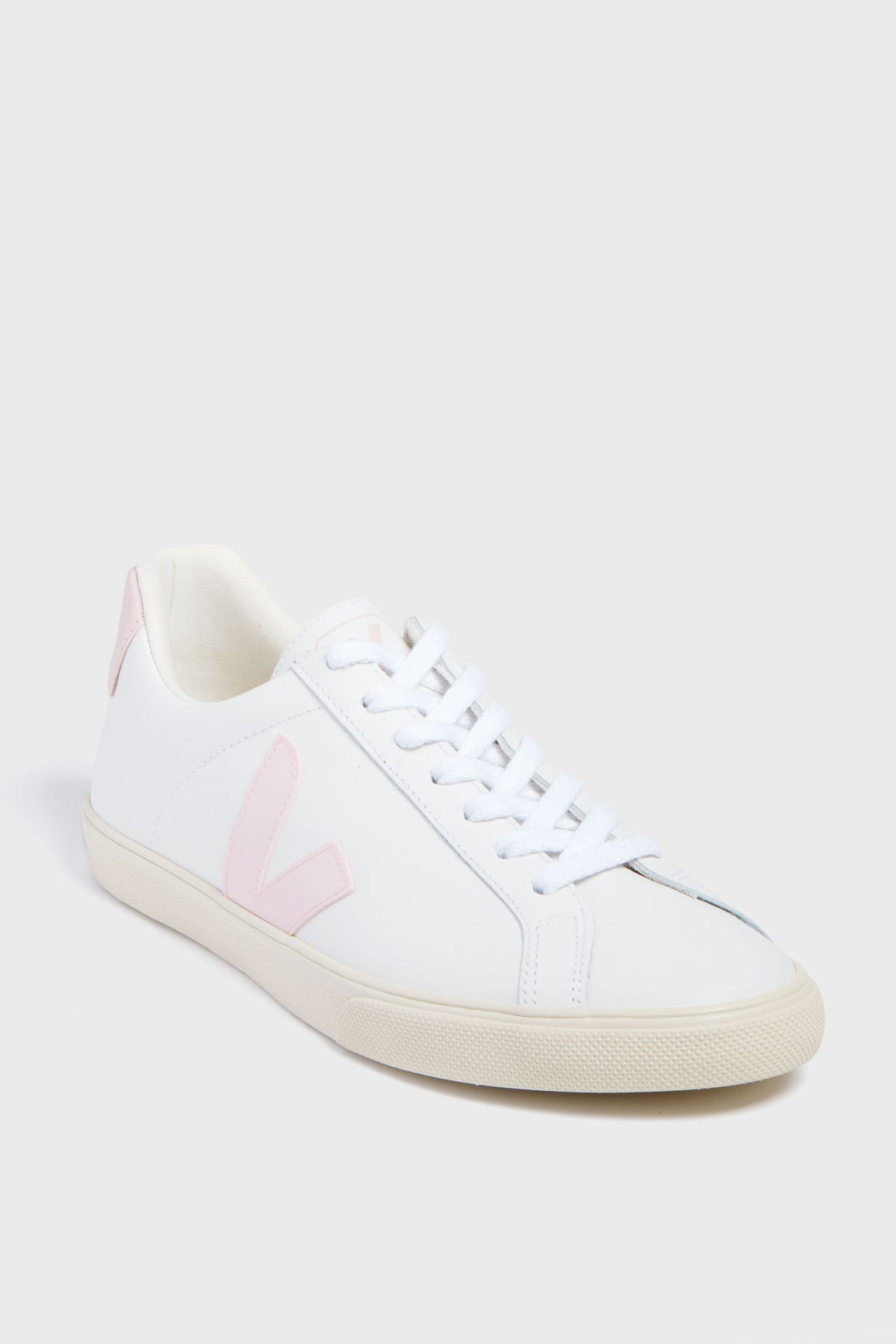The VEJA sneaker features white organic cotton, light pink accents on the side logo and heel tab, white laces, and a beige rubber sole.