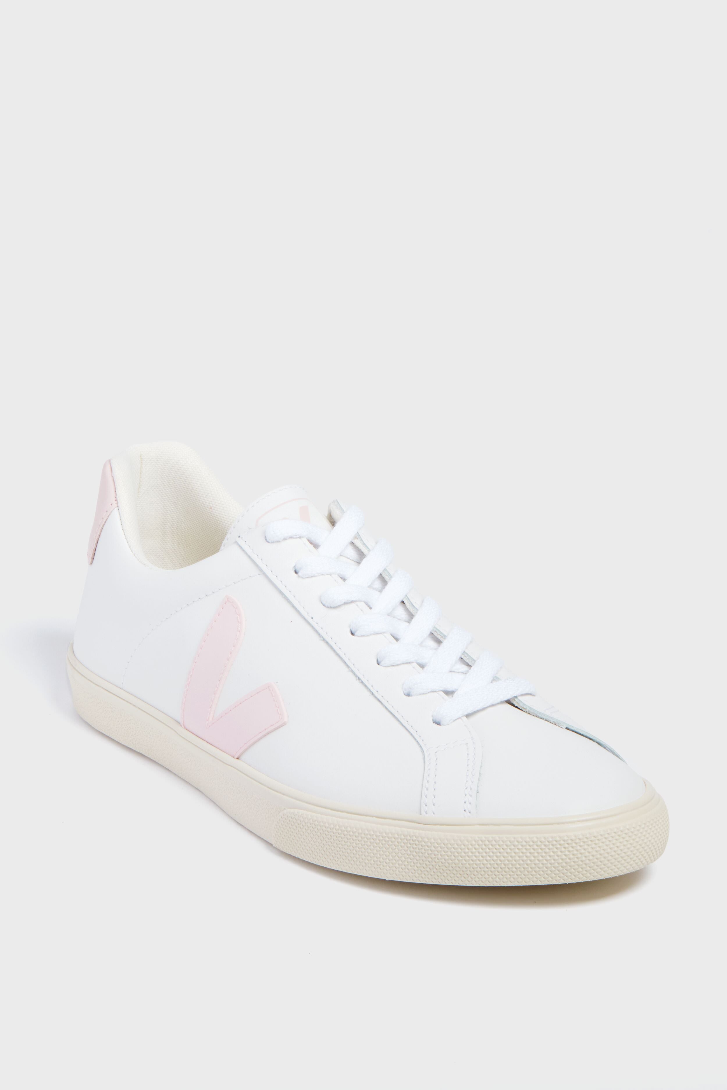 The VEJA sneaker features white organic cotton, light pink accents on the side logo and heel tab, white laces, and a beige rubber sole.