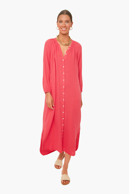 A woman wears a pink XiRENA cotton gauze v-neck summer dress, styled with a gold necklace, hoop earrings, and open-toe sandals as she stands confidently.