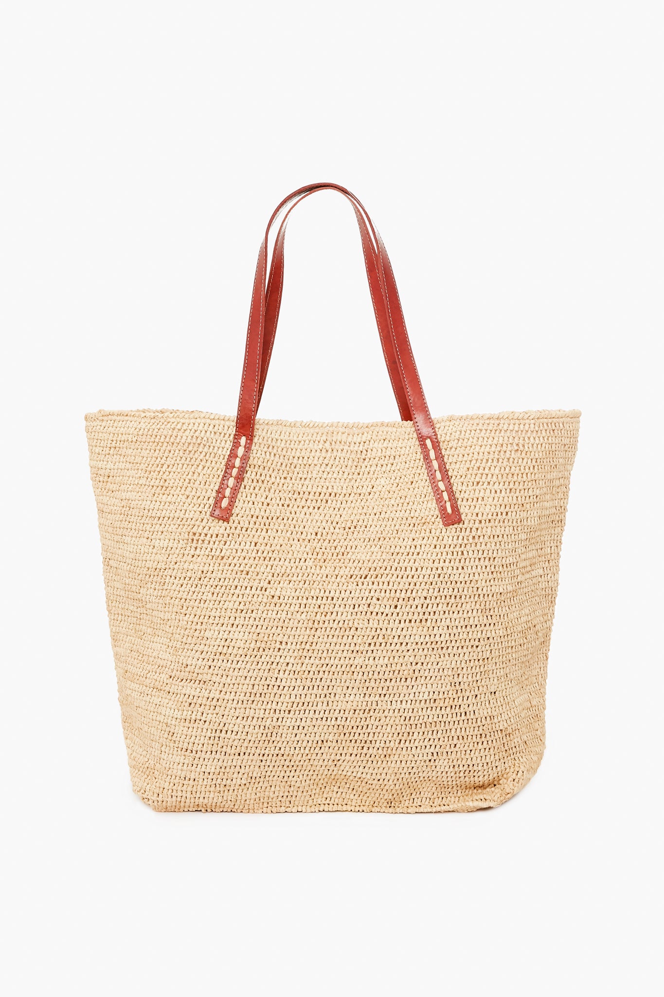 The Mar y Sol tote is a woven raffia bag with brown leather shoulder straps, handmade in Madagascar from sustainable materials.