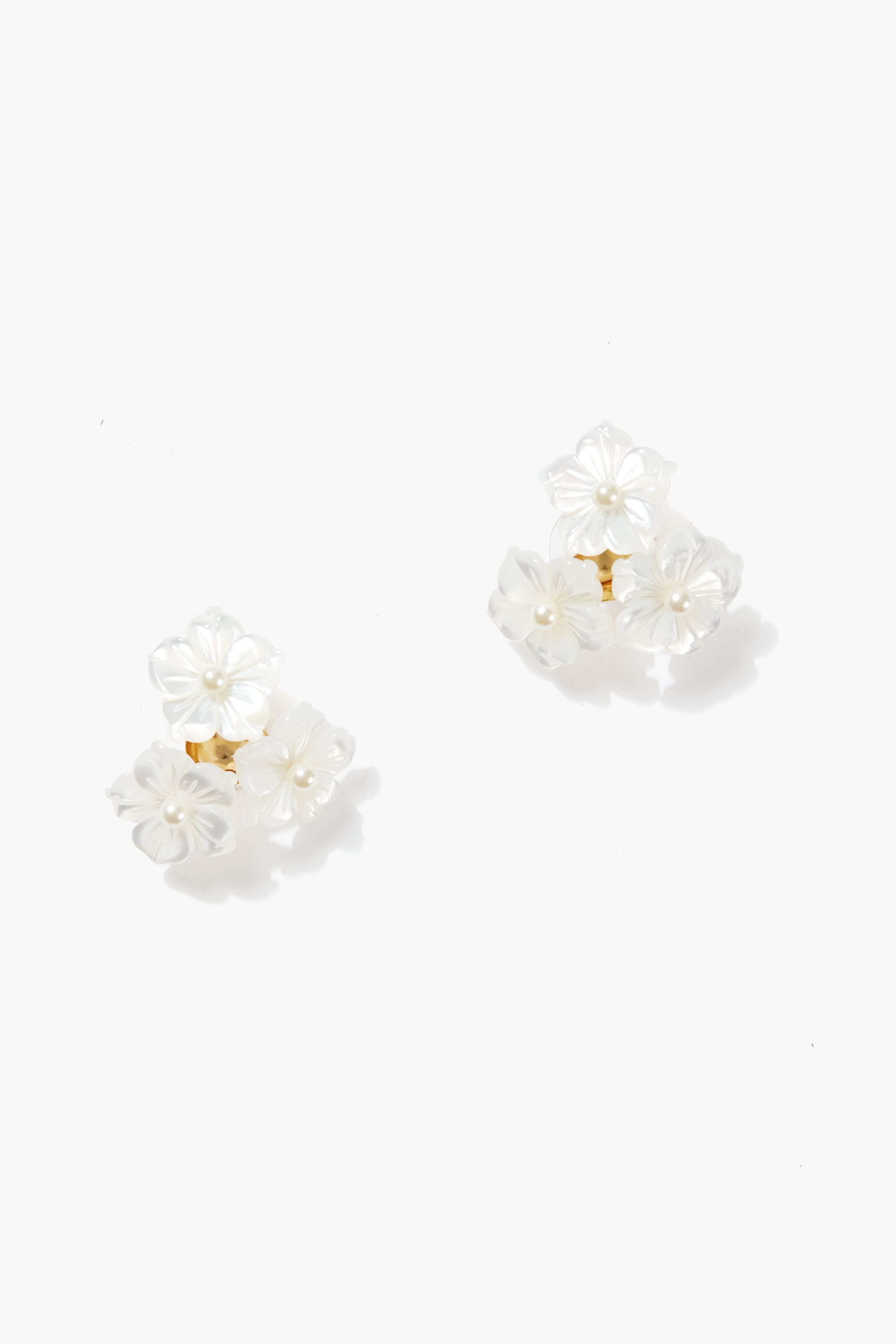 A pair of Jennifer Behr Marti earrings featuring clusters of small, white, flower-shaped elements with gold centers—handmade in New York.