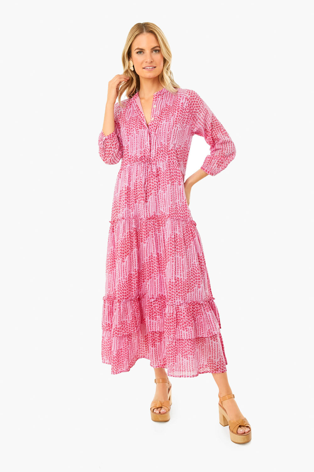 A woman wears a pink and white Banjanan dress featuring handmade embroidery and a collar, paired with tan platform sandals.