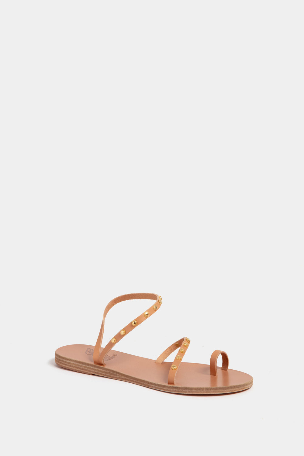 Ancient Greek Sandals tan flat sandal featuring thin leather straps, gold stud accents, and a toe loop.