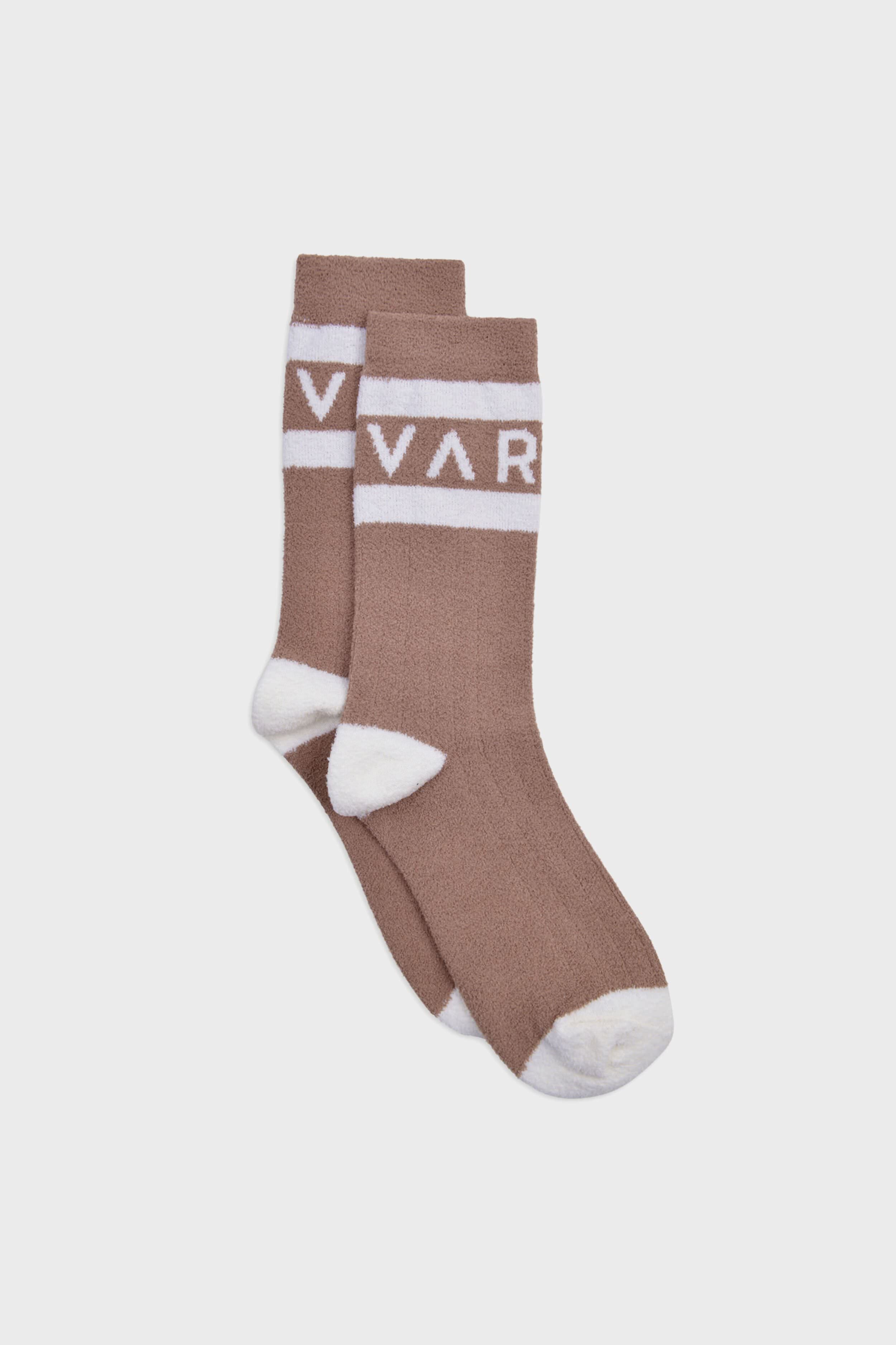 A pair of brown boucle crew socks by Varley with white toes, heels, and cuffs, featuring a white band near the top with "VAR" text.