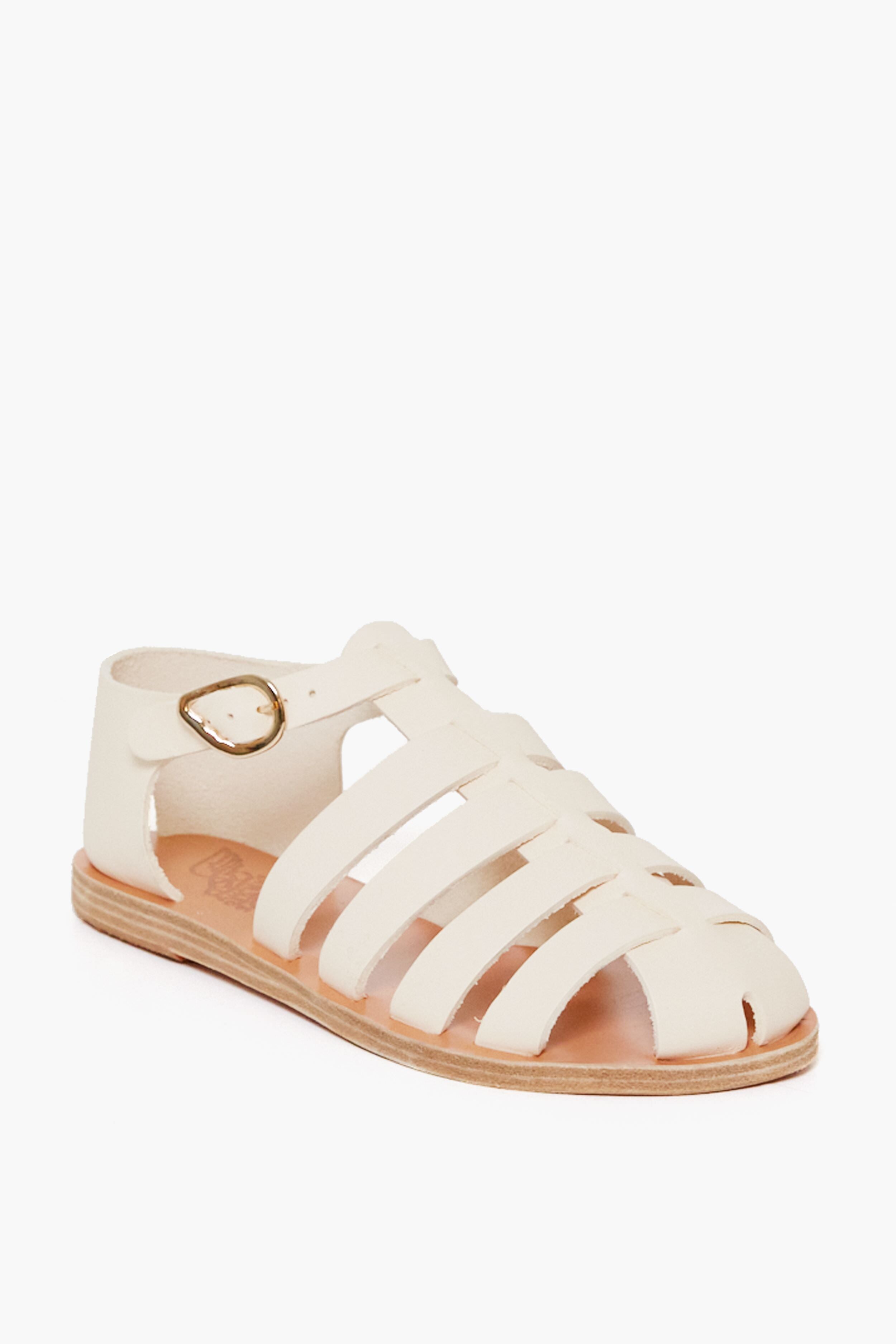 A cream-colored handmade leather fisherman sandal by Ancient Greek Sandals, featuring a closed toe, multiple straps, and a side buckle.