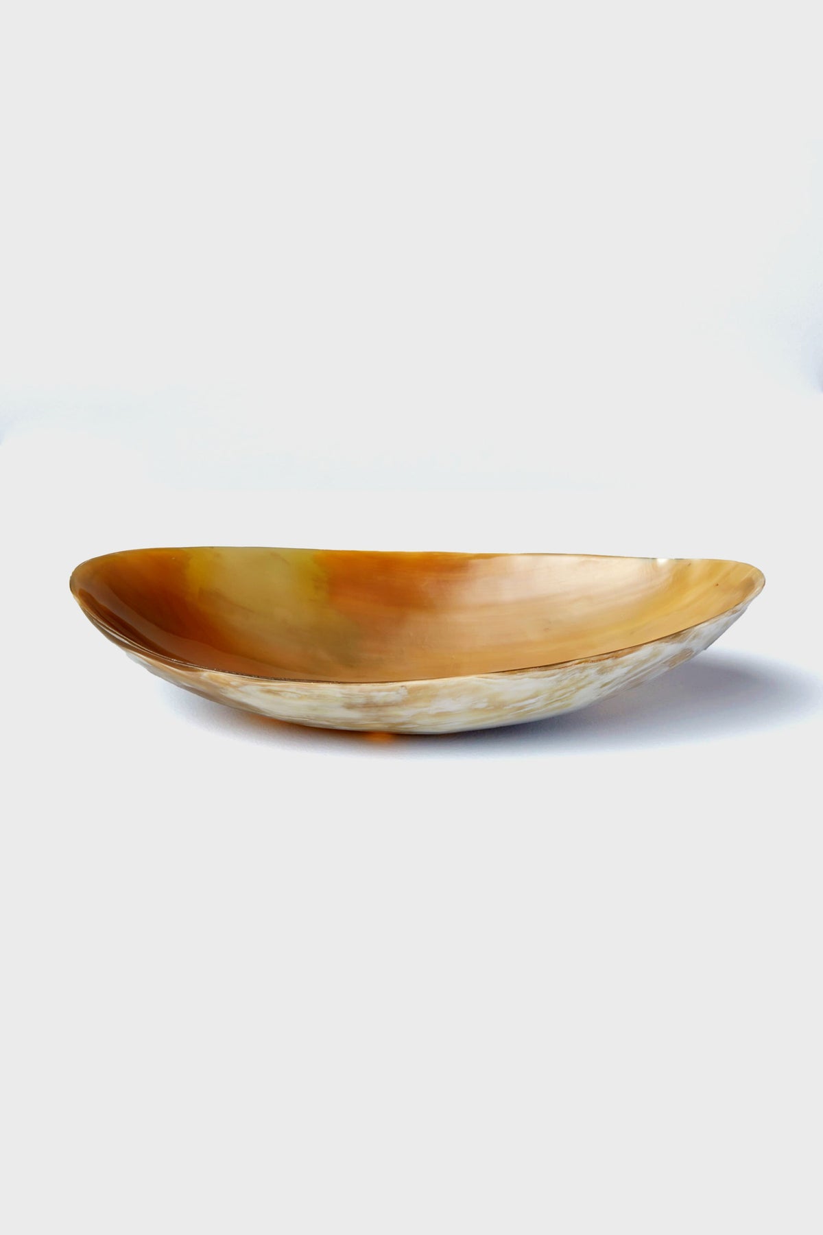 The Be Home oval-shaped, shallow horn bowl features a polished amber-toned surface and smooth texture. Handcrafted and ethically sourced, it's perfect for those who appreciate unique home goods.