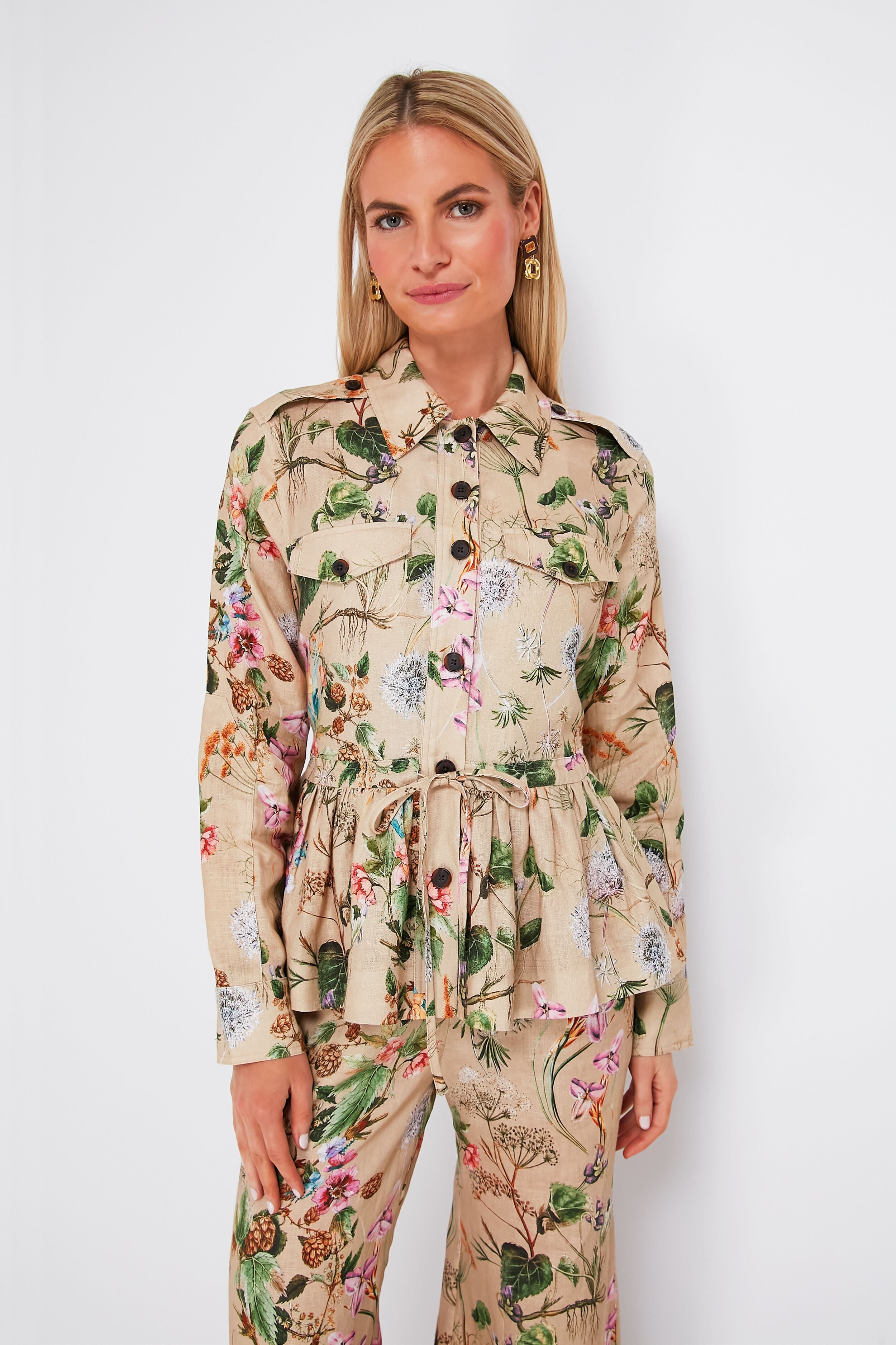 A woman wears a Cara Cara beige floral print linen peplum jacket with waist tie and matching pants, styled for a chic look.