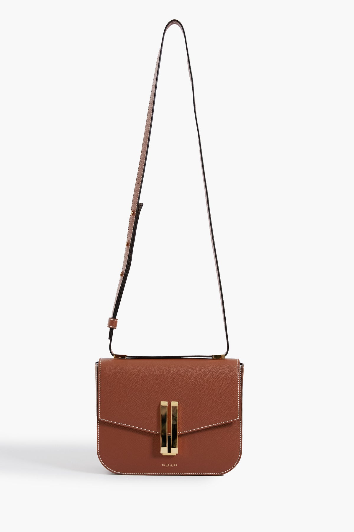 A brown cowhide leather shoulder bag by Demellier, featuring white stitching, a gold-tone rectangular clasp, and an adjustable strap—expertly crafted as part of our handcrafted handbags collection.