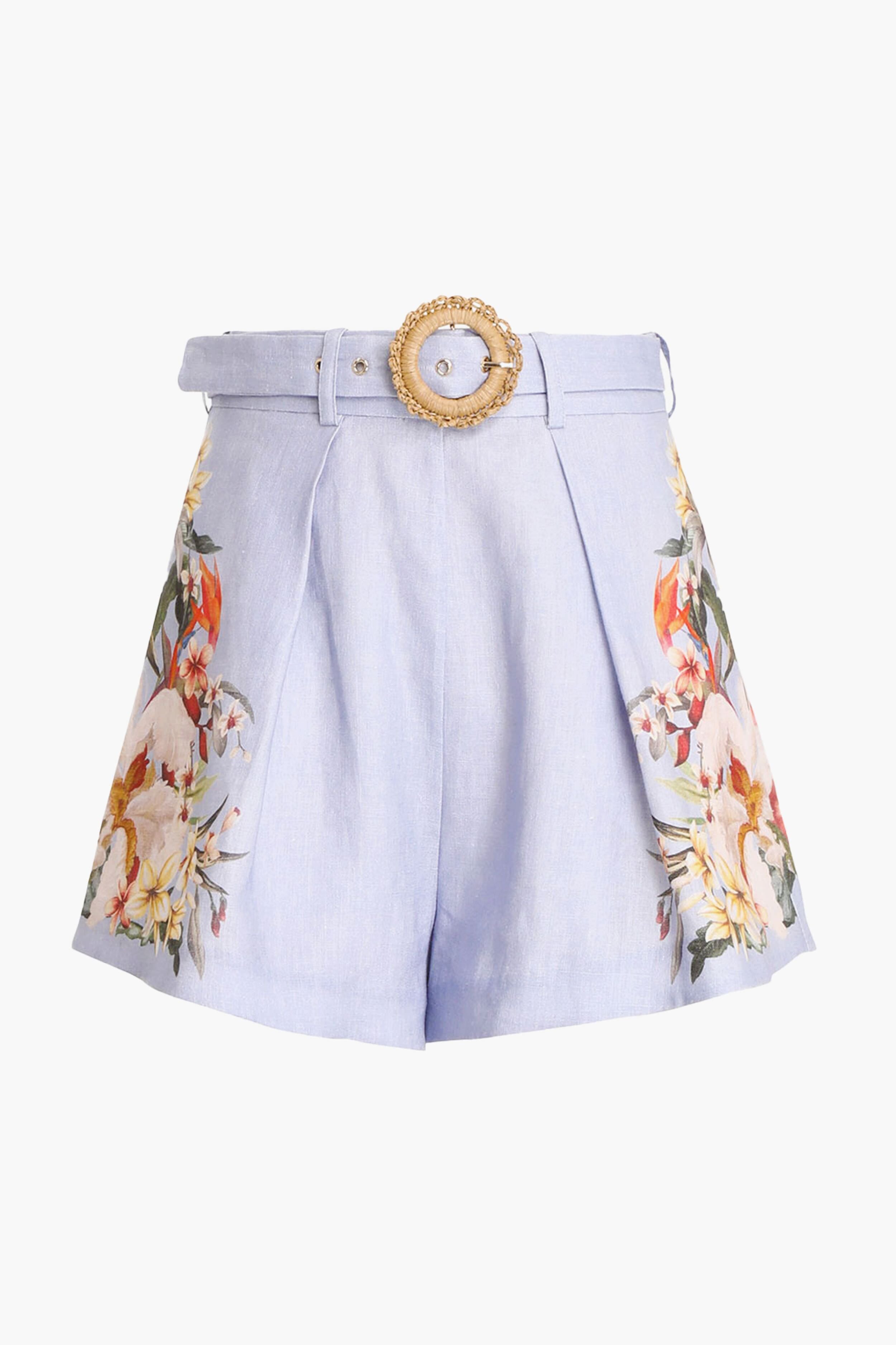 Zimmermann light blue high-rise linen shorts with side floral embroidery, pleats, and a decorative round buckle belt, inspired by the brand's elegant style.