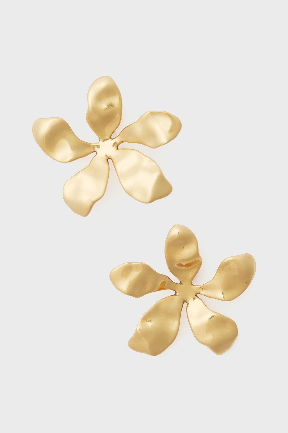 Mignonne Gavigan's Antique Gold Tangier Earrings feature two gold-toned metal earrings shaped like abstract flowers with six irregular petals each—perfect for lovers of unique floral jewelry.