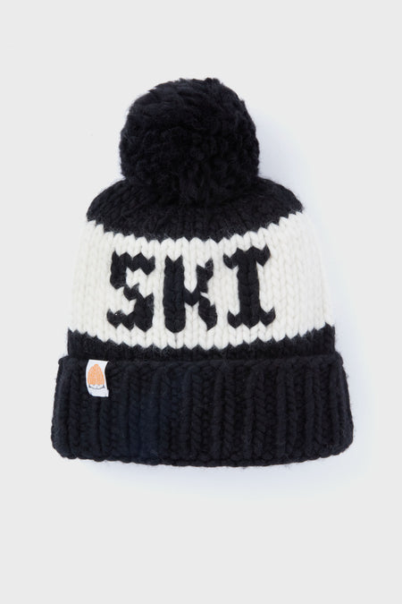 Handcrafted by Lele Sadoughi, this black and white beanie features a pom-pom top, bold SKI lettering on the front, and a small patch sewn onto the folded brim for extra style.