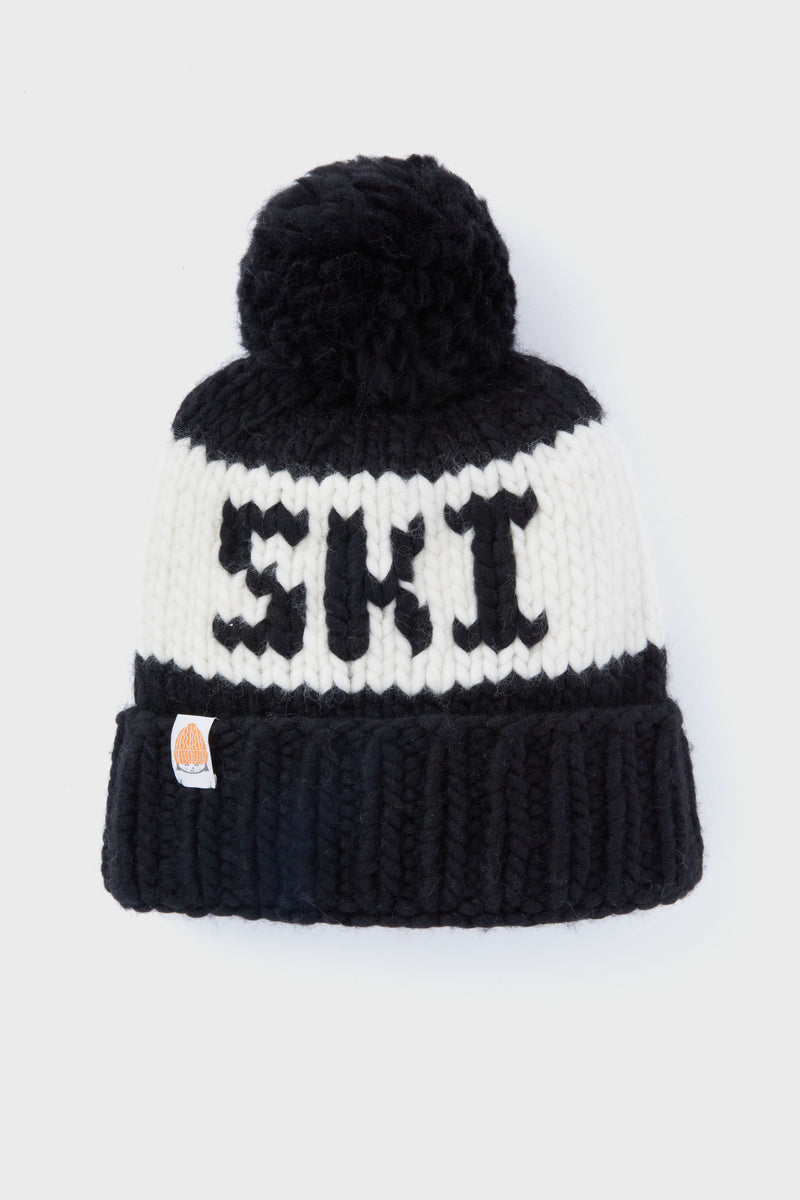 Handcrafted by Lele Sadoughi, this black and white beanie features a pom-pom top, bold SKI lettering on the front, and a small patch sewn onto the folded brim for extra style.