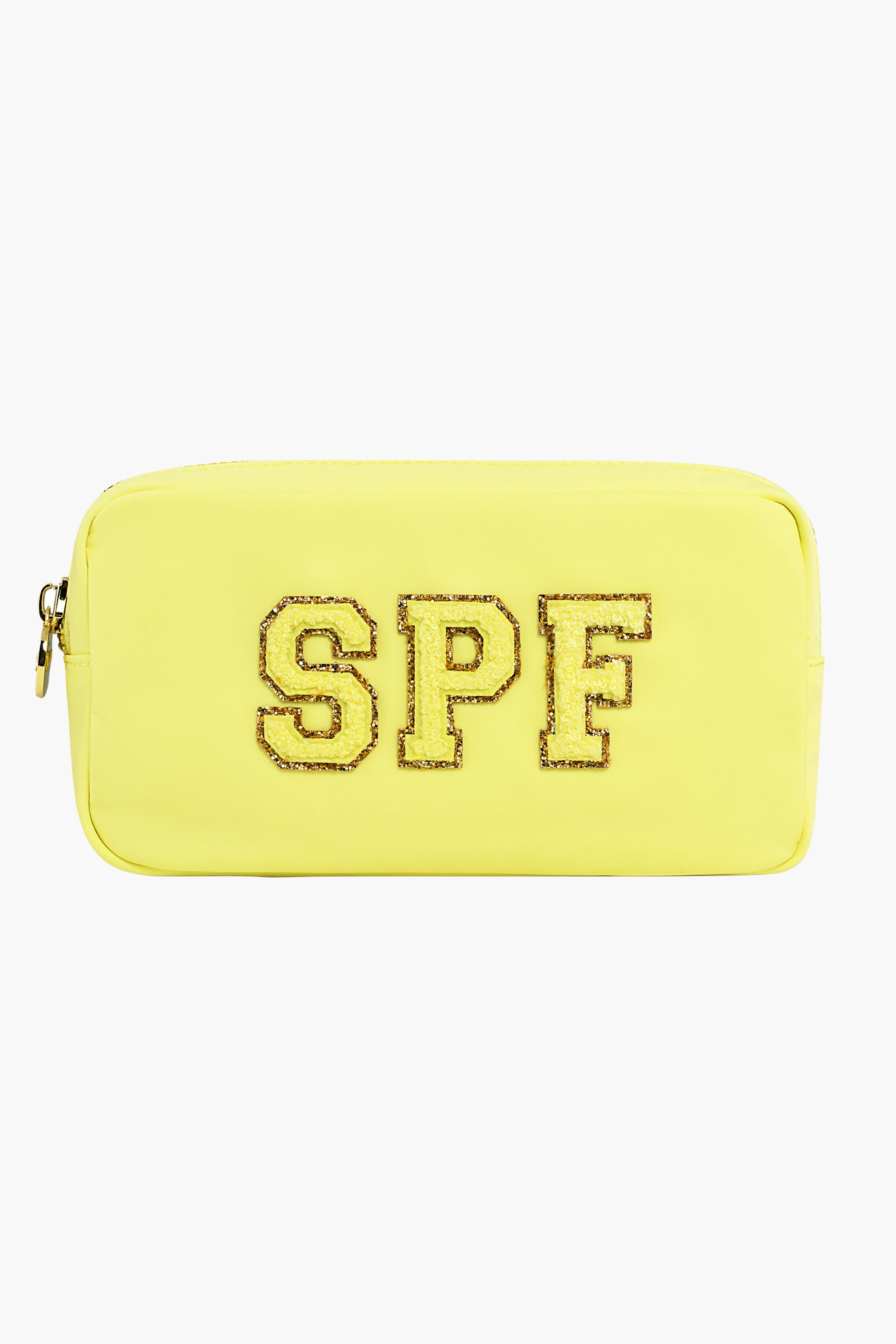 The Stoney Clover Lane rectangular yellow toiletry bag features a zipper and glittery gold-outlined SPF letters on the front—ideal for carrying your travel accessories.
