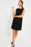 A woman wears the Tuckernuck Black Sydney Dress, a sleeveless mini with front pockets, paired with black espadrille flats.