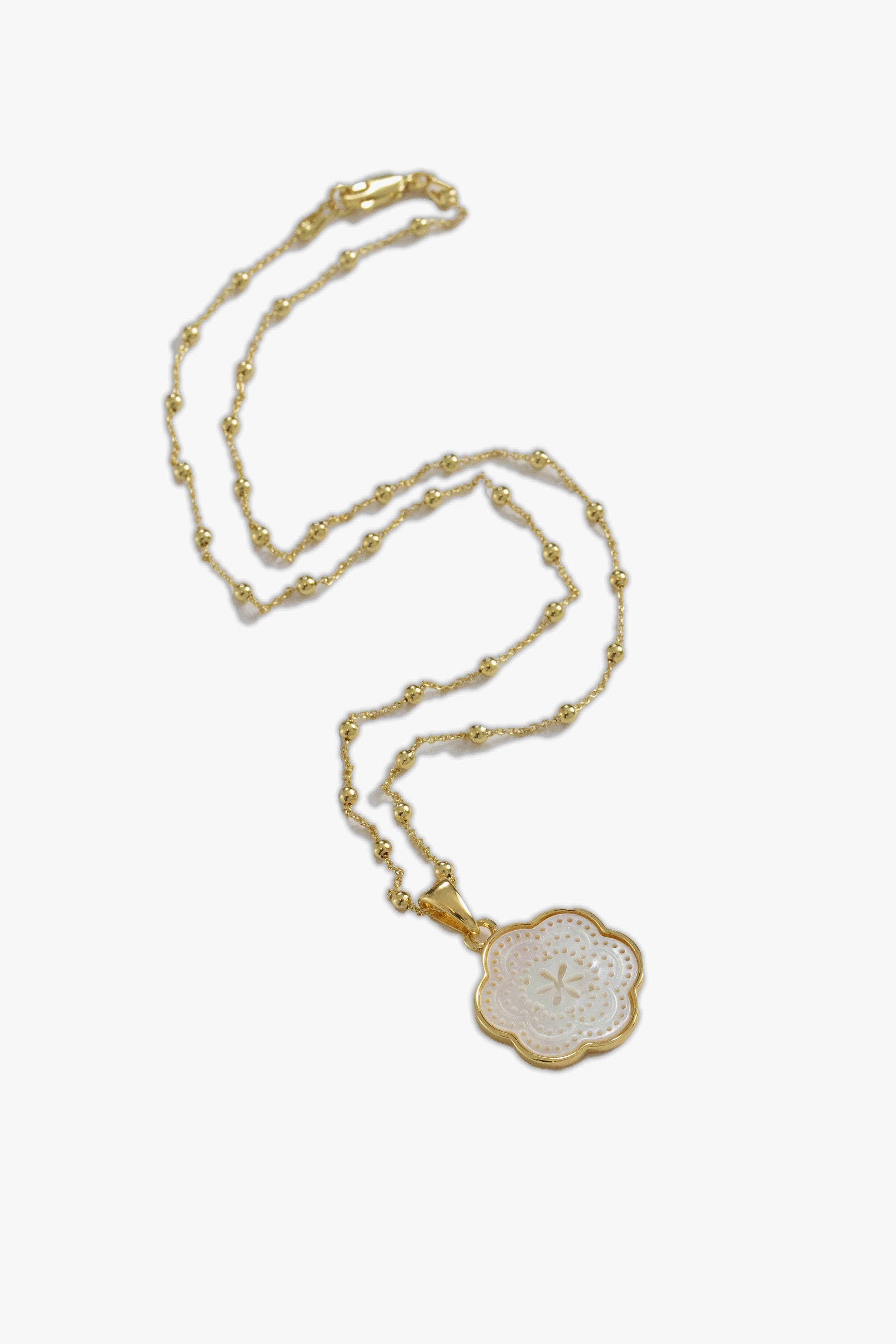 ASHA gold chain necklace featuring small beads and a flower-shaped white enamel mother of pearl pendant with an intricate pattern.