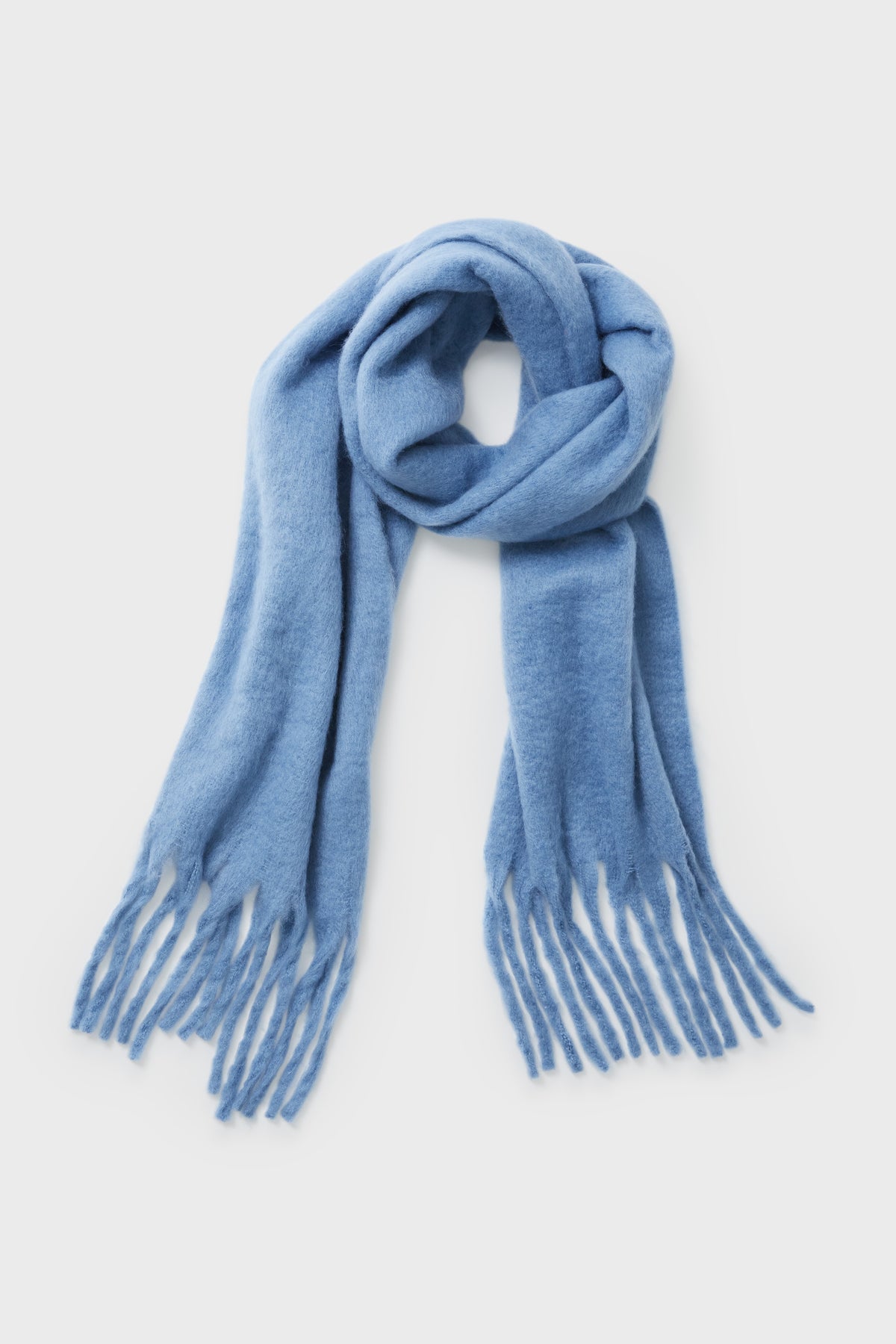 A light blue Hat Attack wool Denim Chic Solid Scarf with fringed ends, stylishly laid out as a cozy cold-weather accessory.