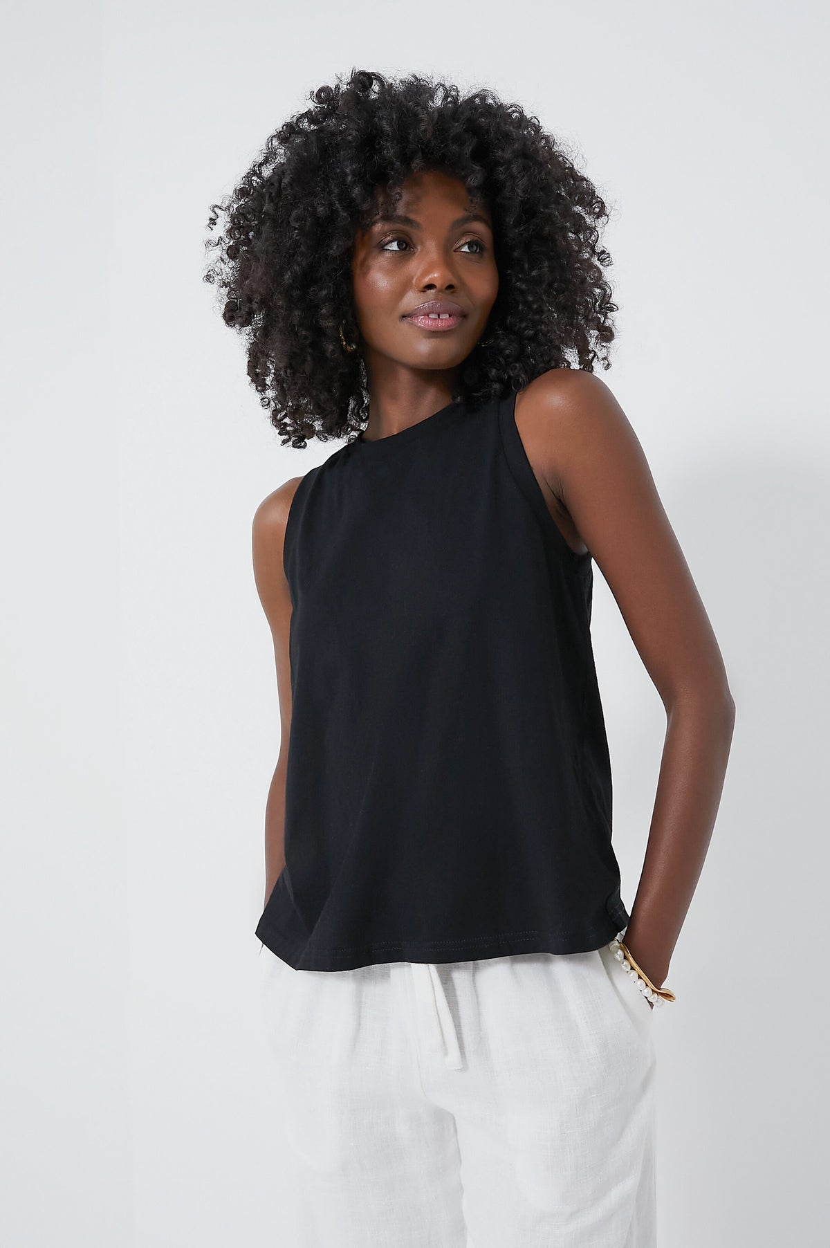 A woman with curly hair wears a cropped cotton tank from Pomander Place.