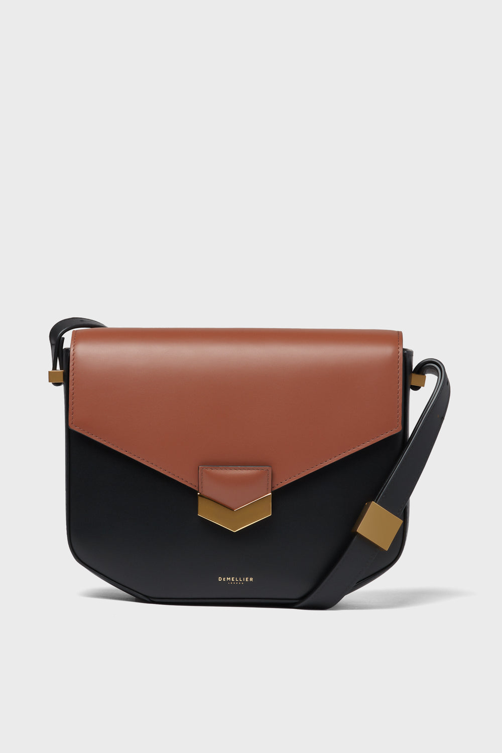 The Demellier crossbody bag features a two-tone design with a brown flap, black body, gold-tone hardware, and an adjustable strap.