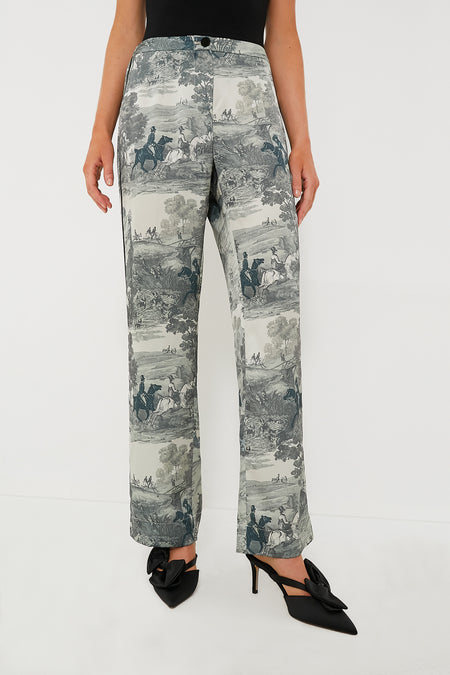 A person styled in high-rise Tuckernuck Middleburg Toile Solene Pants with a scenic print, paired with a black top and black heeled bow shoes.