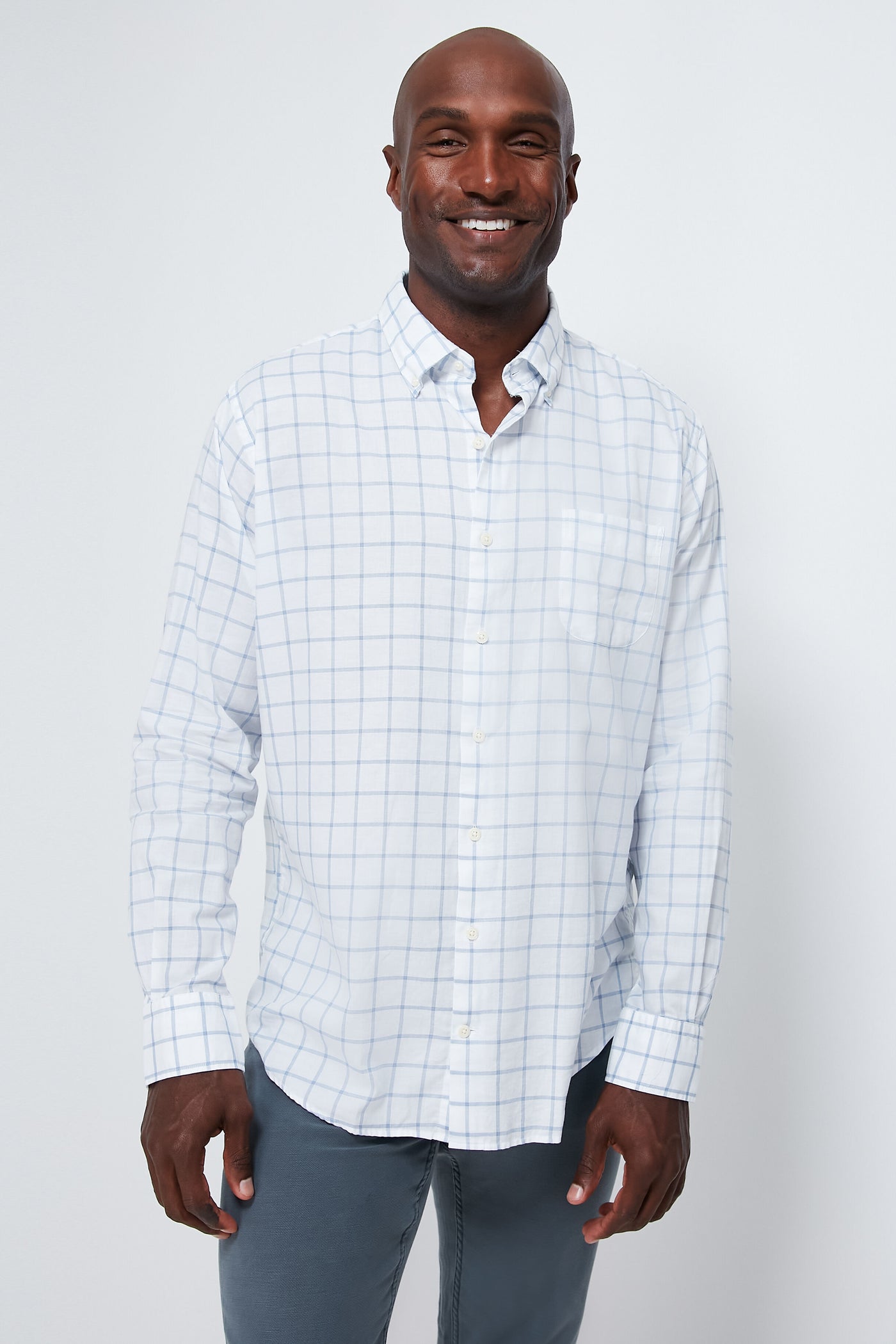 A man smiles confidently wearing a Peter Millar breathable cotton sport shirt featuring a blue checkered pattern and long sleeves.