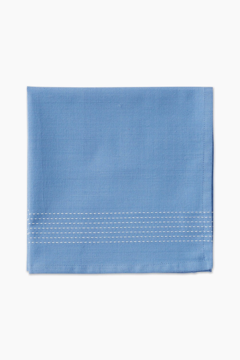 A folded light blue cotton napkin by Caton's Wharf, featuring three rows of white edge stitching, adds a touch of coastal table decor.
