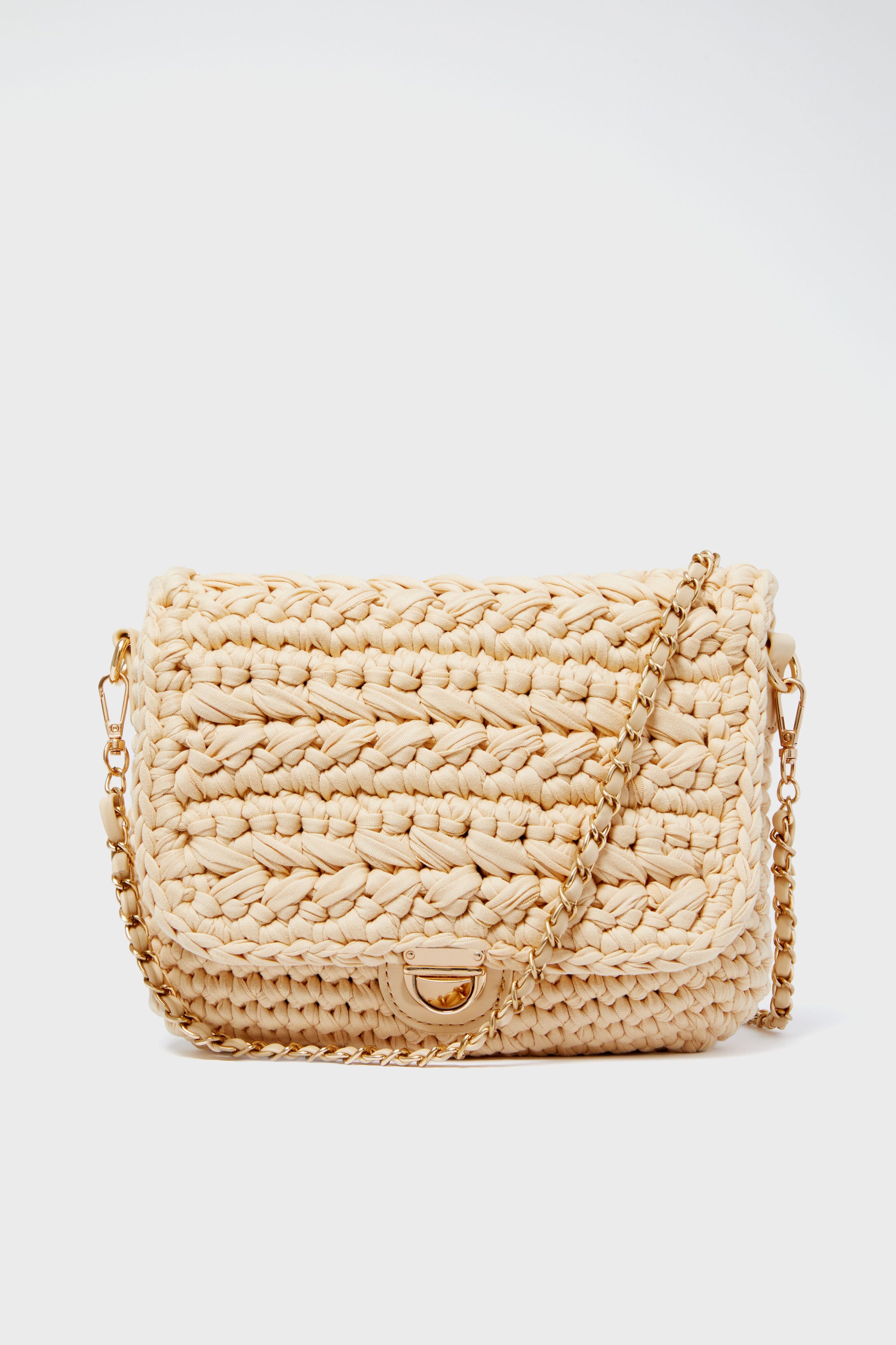 The Moda Luxe Annalise crossbody is a beige woven vegan leather handbag with a flap closure and gold chain strap.