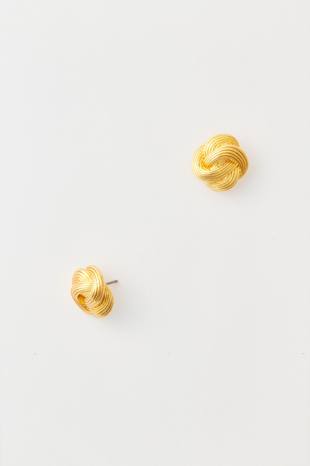 The image shows a pair of Tuckernuck Jewelry gold stud earrings with a classic knot design, crafted from nickel-free materials.