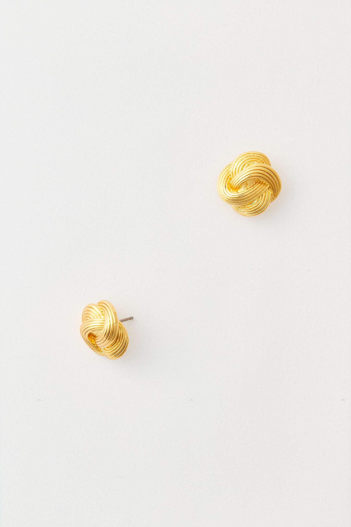 The image shows a pair of Tuckernuck Jewelry gold stud earrings with a classic knot design, crafted from nickel-free materials.