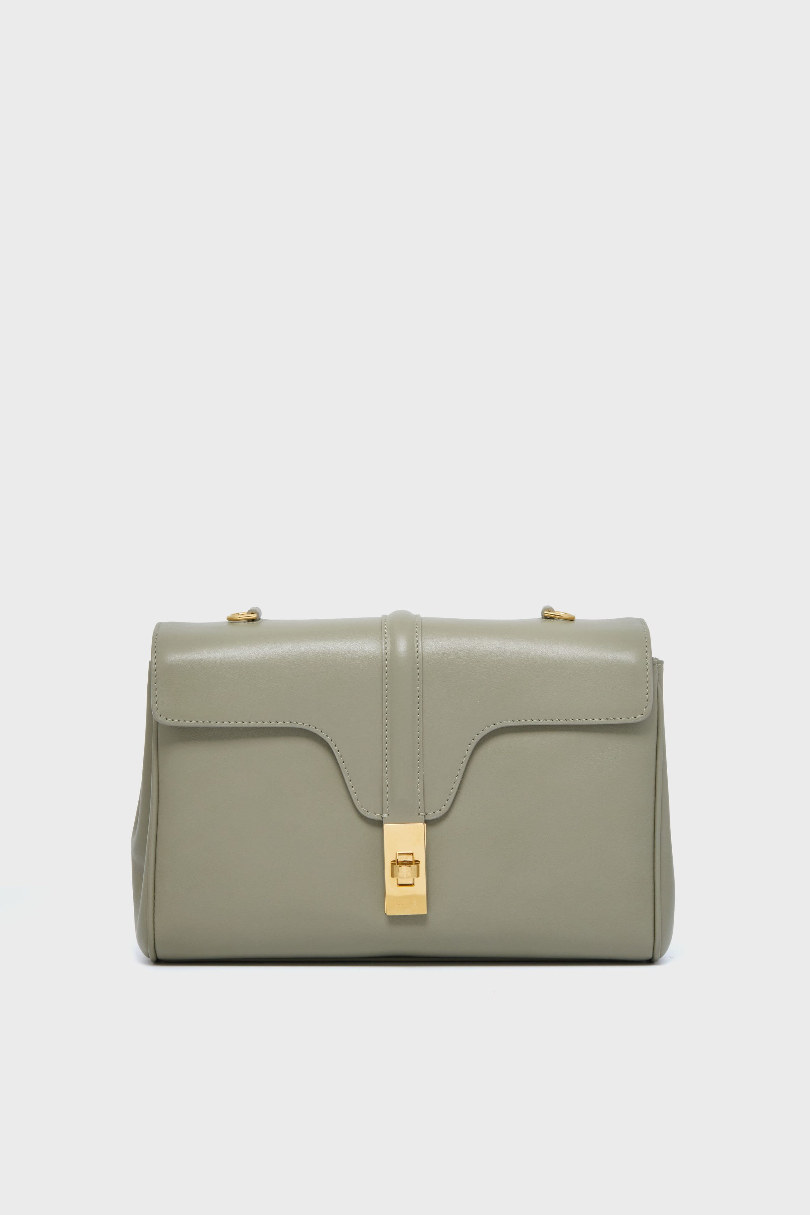 A rectangular, light gray luxury leather handbag from the Tuckernuck Archive Collection, featuring a flap closure and gold-tone hardware—central clasp and two top studs—reminiscent of the Celine Teen Soft 16 Bag.