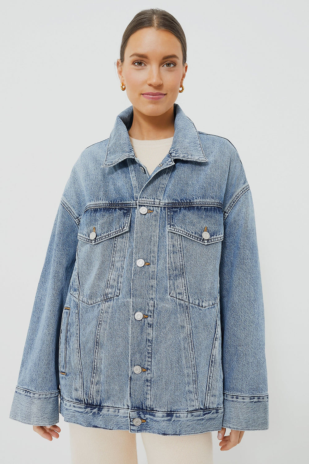 A woman wears an AGOLDE vintage-inspired oversized denim jacket in light blue organic cotton, featuring a button closure and front flap pockets.