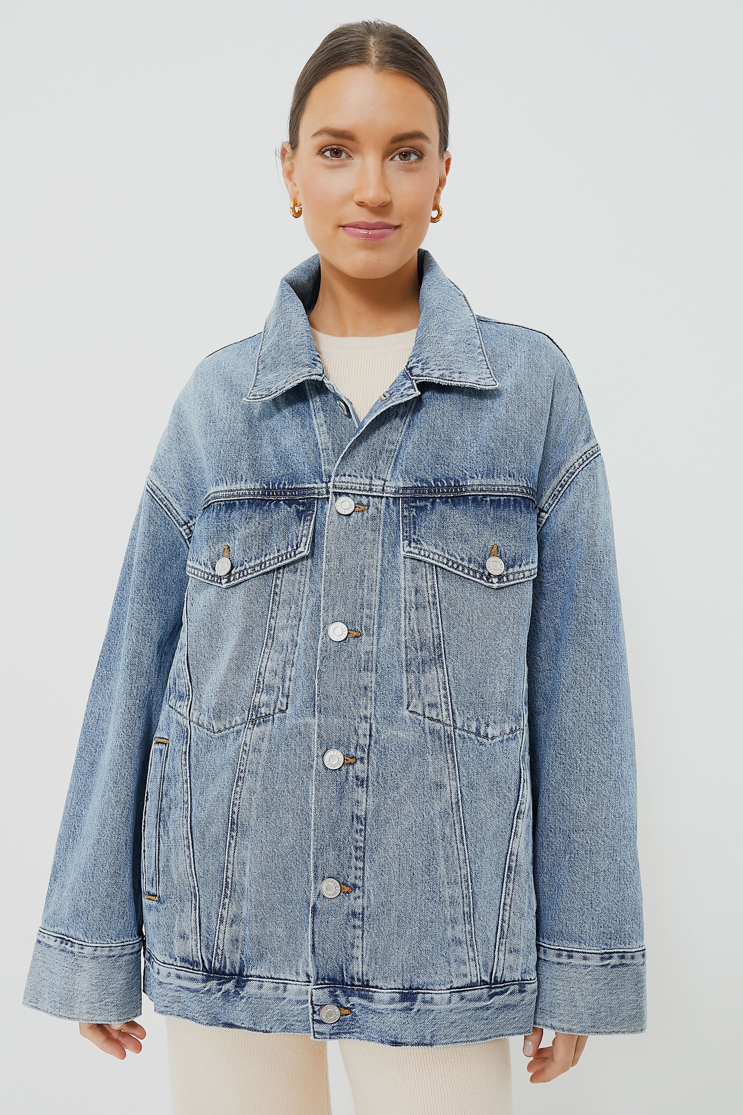 A woman wears an AGOLDE vintage-inspired oversized denim jacket in light blue organic cotton, featuring a button closure and front flap pockets.