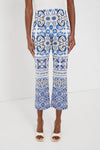 A person wears Tuckernuck blue and white majolica tile print pants with flared legs, paired with white open-toe heels.