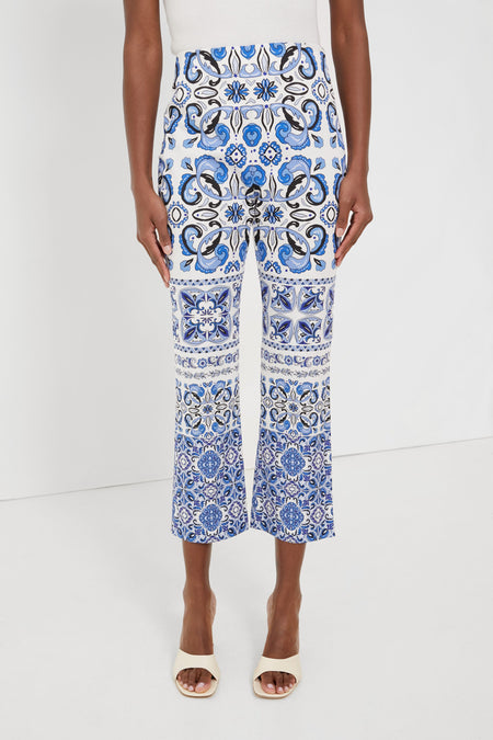 A person wears Tuckernuck blue and white majolica tile print pants with flared legs, paired with white open-toe heels.