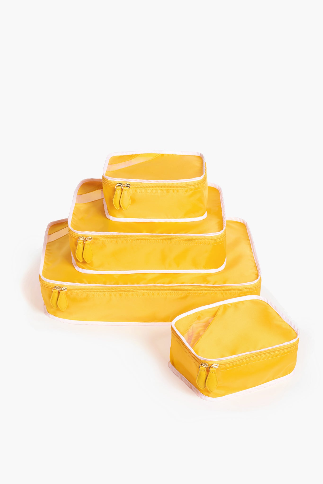 Four yellow zippered packing cubes of varying sizes from Paravel are stacked, ideal for travel organization or pairing with sustainable luggage.