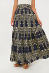A person wears an Eugenia Fernandez navy blue and yellow patterned cotton maxi skirt with a white top and brown sandals—an effortless, sustainable fashion look.