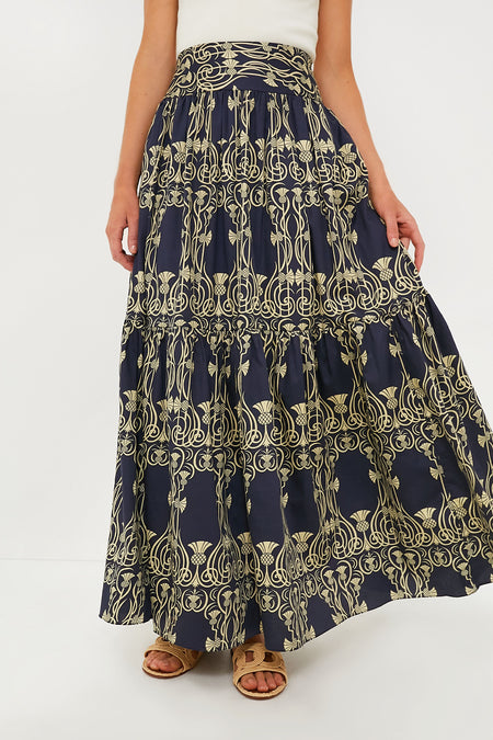 A person wears an Eugenia Fernandez navy blue and yellow patterned cotton maxi skirt with a white top and brown sandals—an effortless, sustainable fashion look.